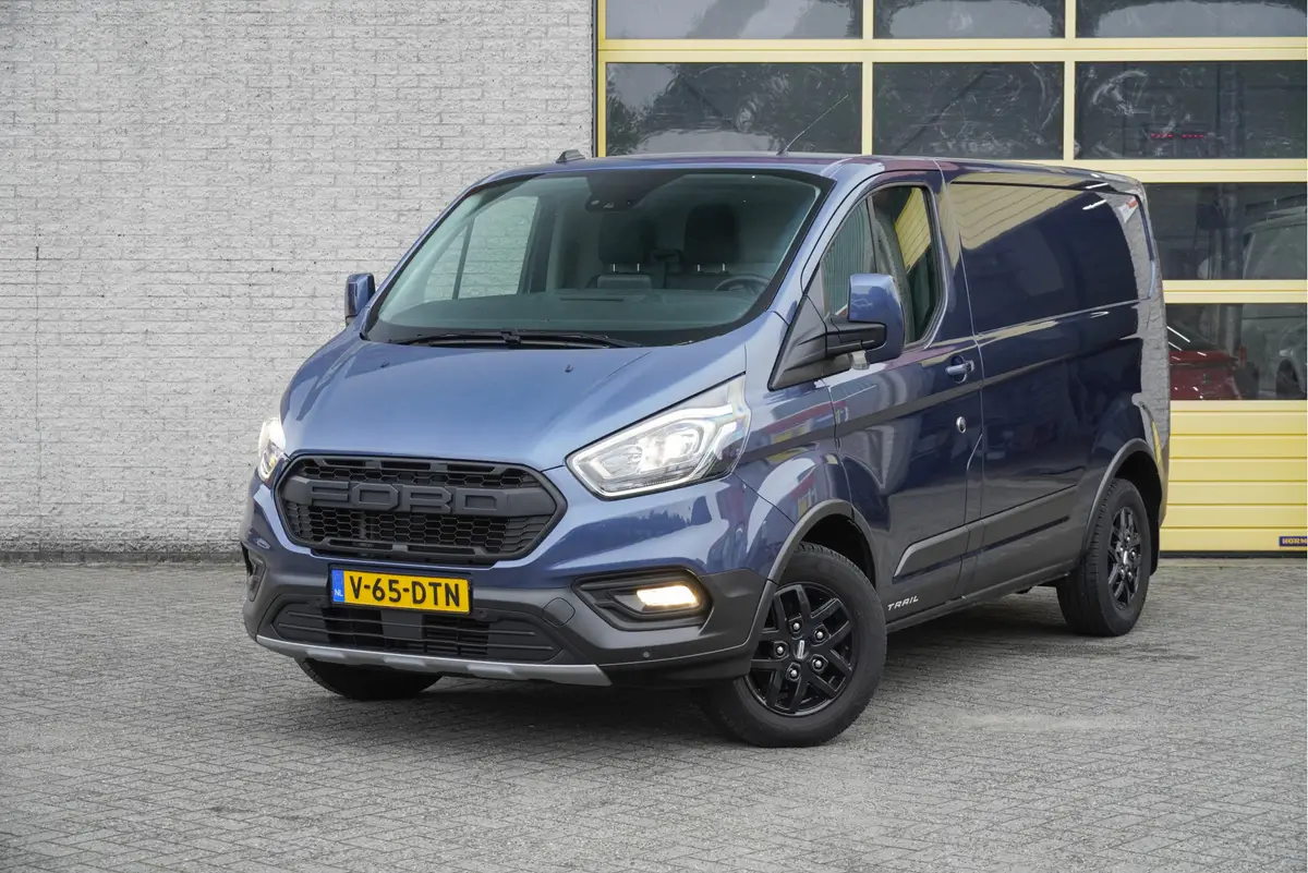 Ford Transit Custom 300 2.0 TDCI L1H1 Trail BJ2022 Lmv 16" (Zwart) | Led | Pdc | Trekhaak | Verwarmde voorruit | Achteruitrijcamera | Navi | Airco | Cruise control | Lederen bekleding | Verwarmde voorstoelen | Tussenschot | Achterdeuren | Zijdeur | Bijrijdersbank|3 Persoons: foto 1